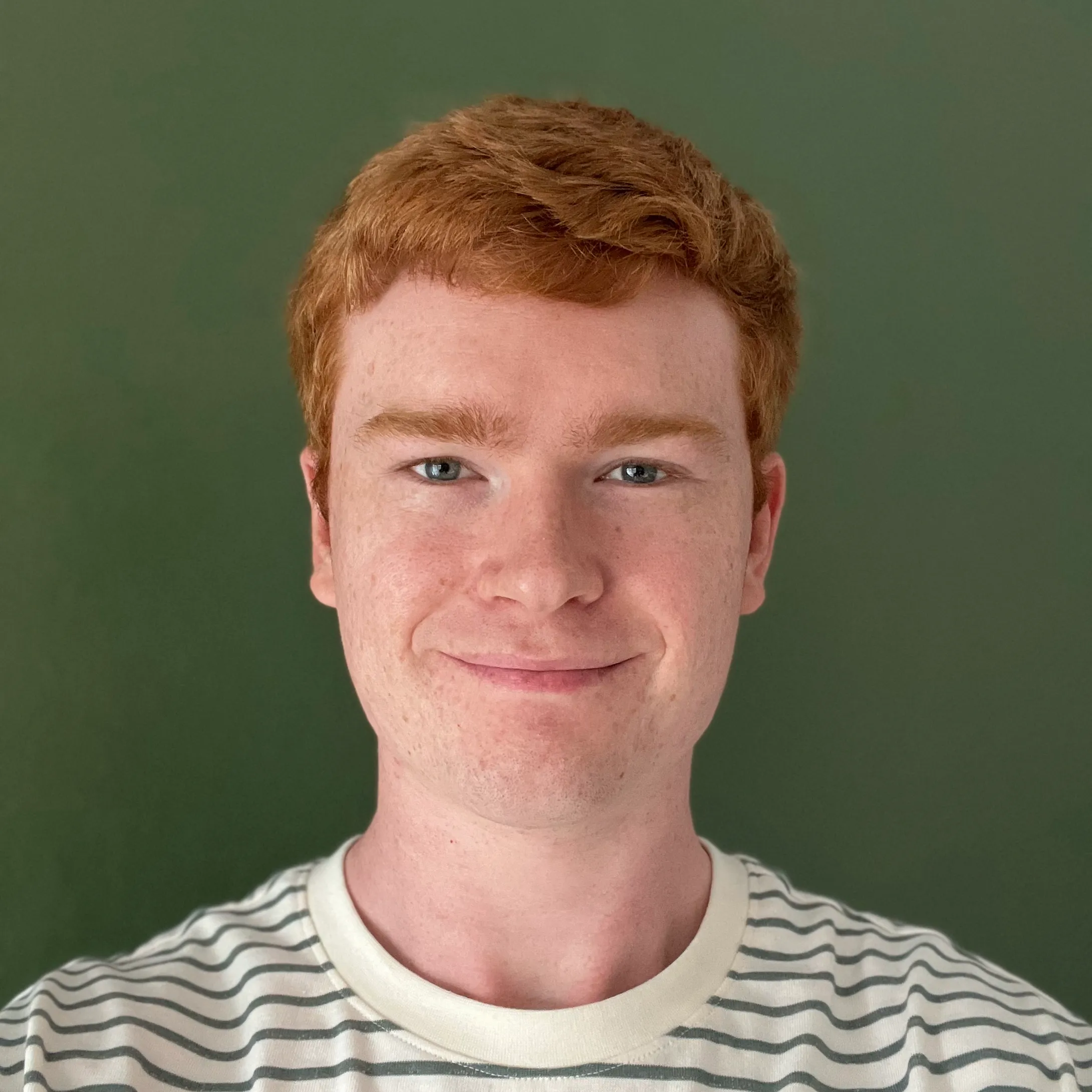 A photo of Daniel, a smiling man with ginger hair, wearing a green and white striped shirt, facing the camera